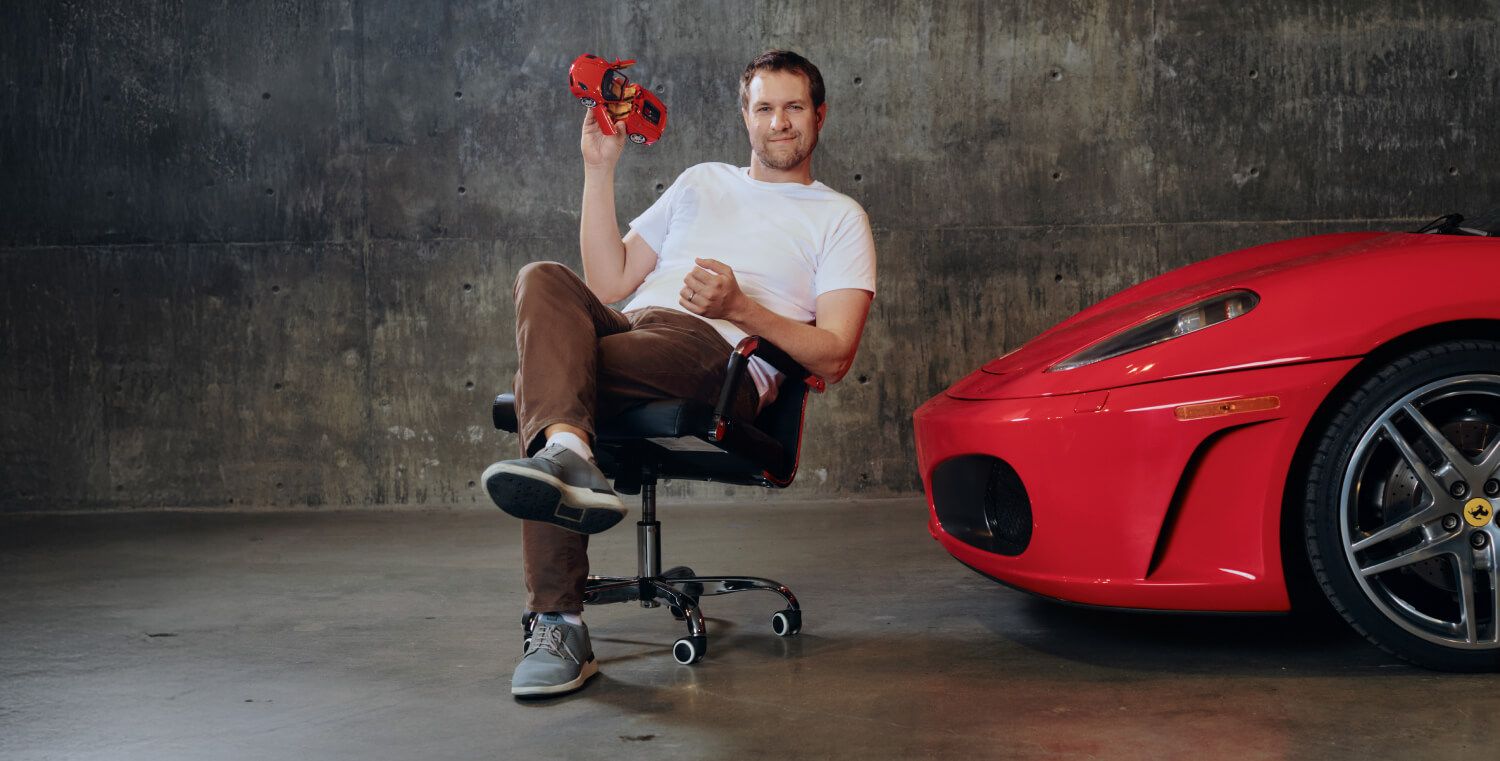 Doug DeMuro sitting next to a red Ferrari F430