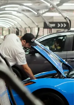 Man looking under the hood of a blue car in a parking garage