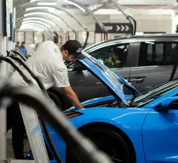 Man looking under the hood of a blue car in a parking garage