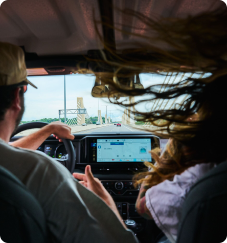 An image from the backseat of a couple in the driver and passenger seats of a car.
