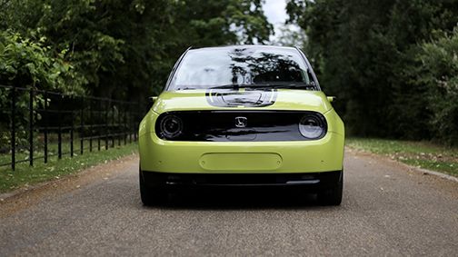 Front view of neon green and black Honda e on country road