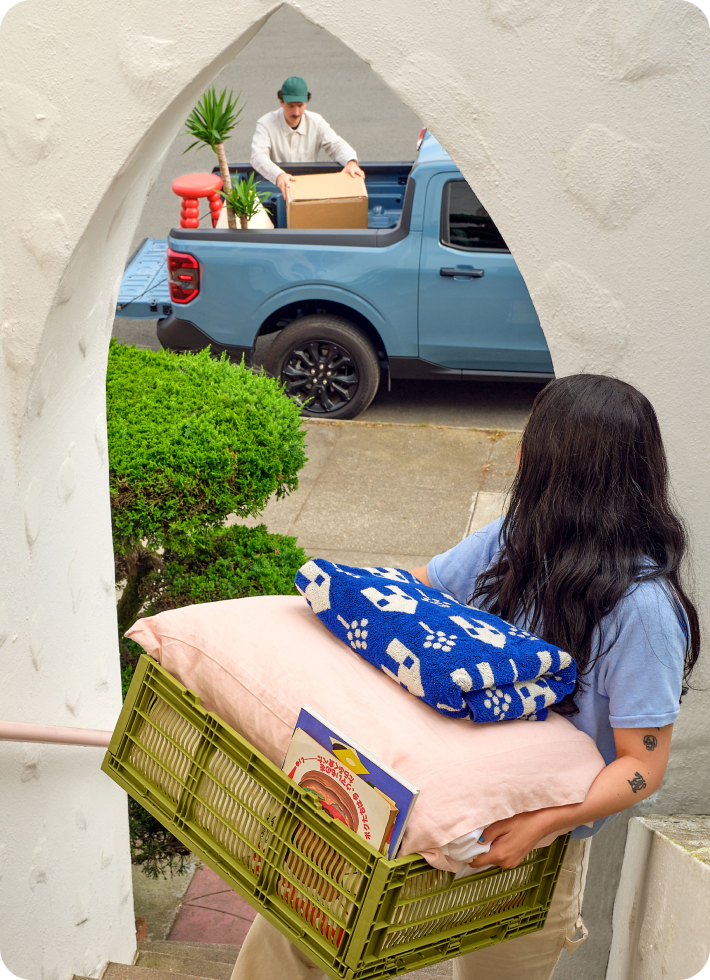 Two young people moving stuff from a pickup into their new home.