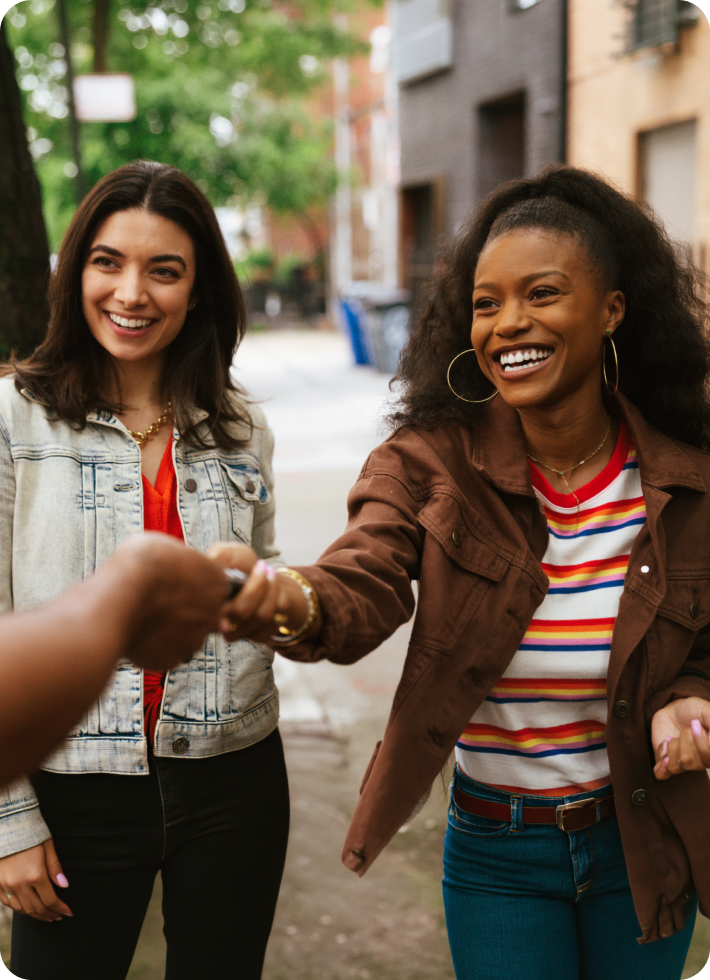 Two friends smile as they’re handed a set of car keys.