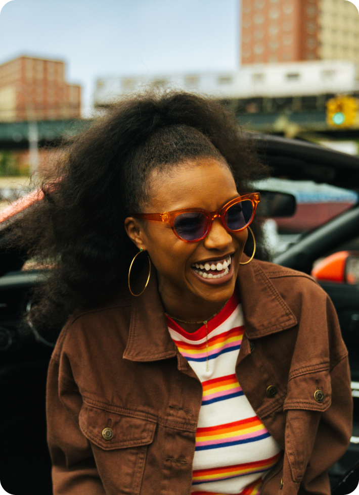 A woman laughing as she steps out of a car.
