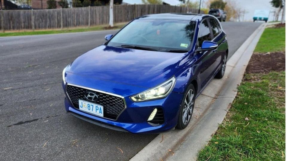 A Turo guest stands next to a Polestar rental car in Melbourne, with the beach in the background