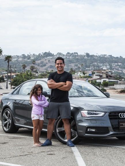 Turo car sharing entrepreneur standing in front of Audi with daughter