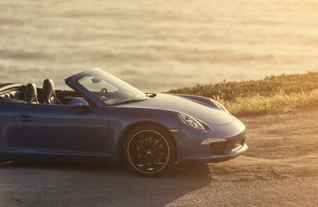 Car sitting next to the ocean in the sunset