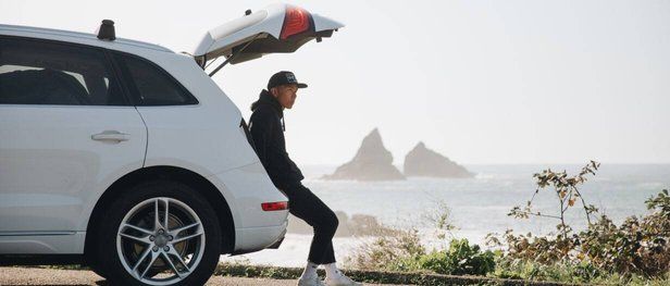 Man sitting in trunk of white Audi by the coast