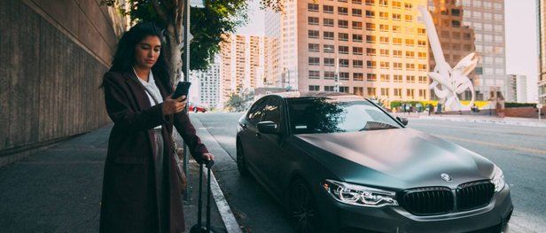 Guest looking at phone next to a BMW