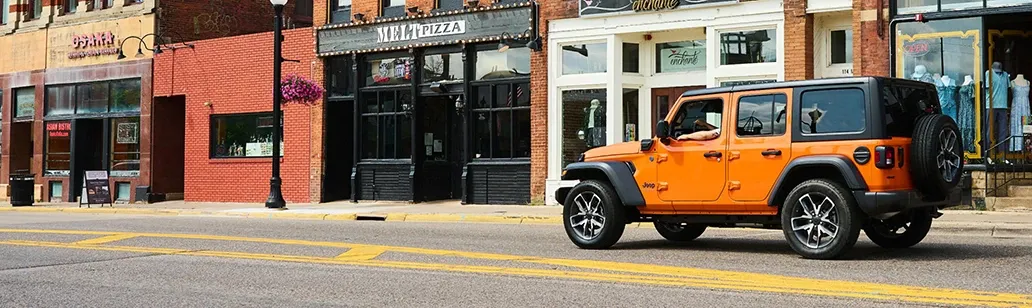 orange suv driving through urban setting