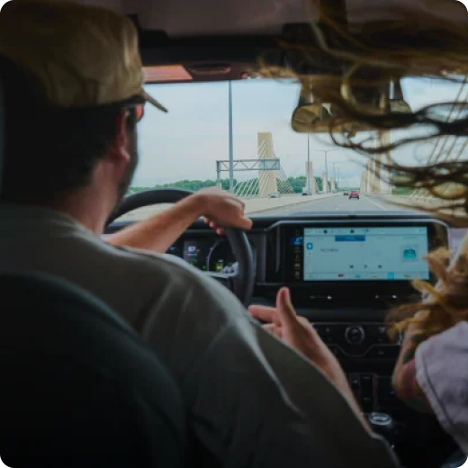 A driver and his passenger chat while driving across a white bridge.