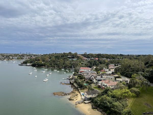 An aerial photo taken of Gladesville, with water on the left and a leafy street on the right.