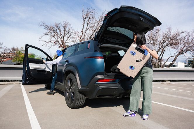 Woman loading suitcase into car