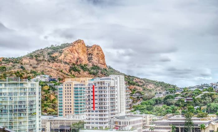 A photo taken in Townsville of buildings and a mountain (Castle Hill) in the background 