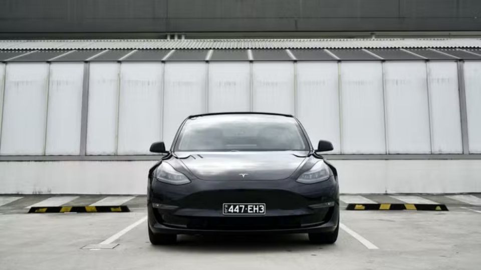 A Turo guest stands next to a Polestar rental car in Melbourne, with the beach in the background