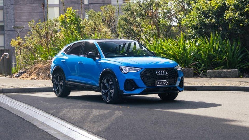 A Turo guest stands next to a Polestar rental car in Melbourne, with the beach in the background