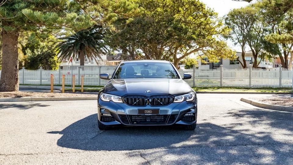 A Turo guest stands next to a Polestar rental car in Melbourne, with the beach in the background