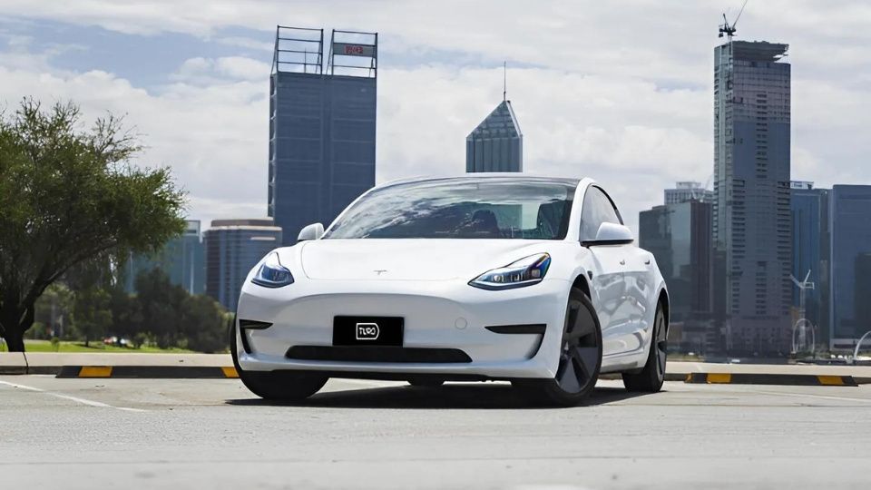 A Turo guest stands next to a Polestar rental car in Melbourne, with the beach in the background
