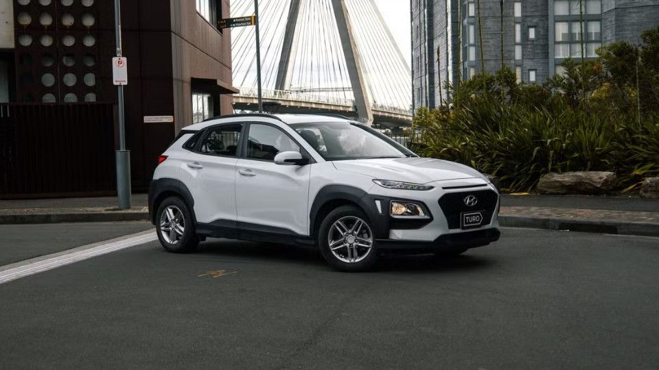 A Turo guest stands next to a Polestar rental car in Melbourne, with the beach in the background