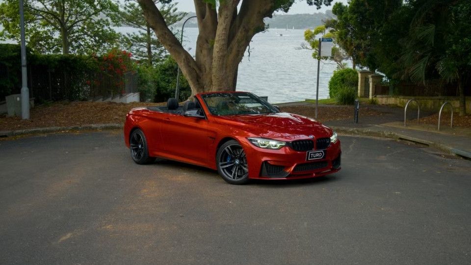 A Turo guest stands next to a Polestar rental car in Melbourne, with the beach in the background