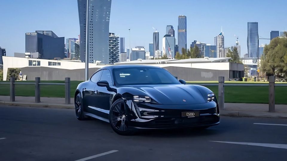 A Turo guest stands next to a Polestar rental car in Melbourne, with the beach in the background