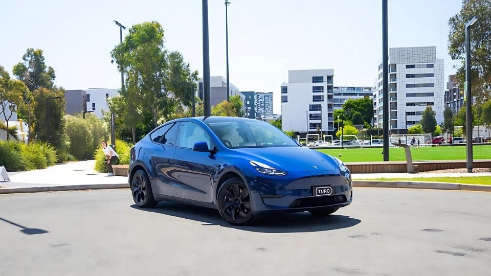 A Turo guest stands next to a Polestar rental car in Melbourne, with the beach in the background