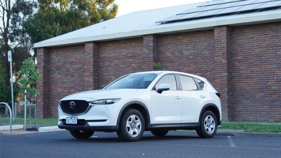 A Turo guest stands next to a Polestar rental car in Melbourne, with the beach in the background