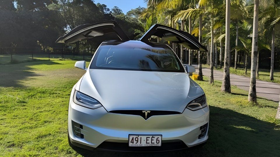 A Turo guest stands next to a Polestar rental car in Melbourne, with the beach in the background