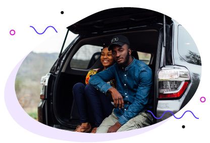 Couple sitting in hatchback trunk of SUV rented on Turo